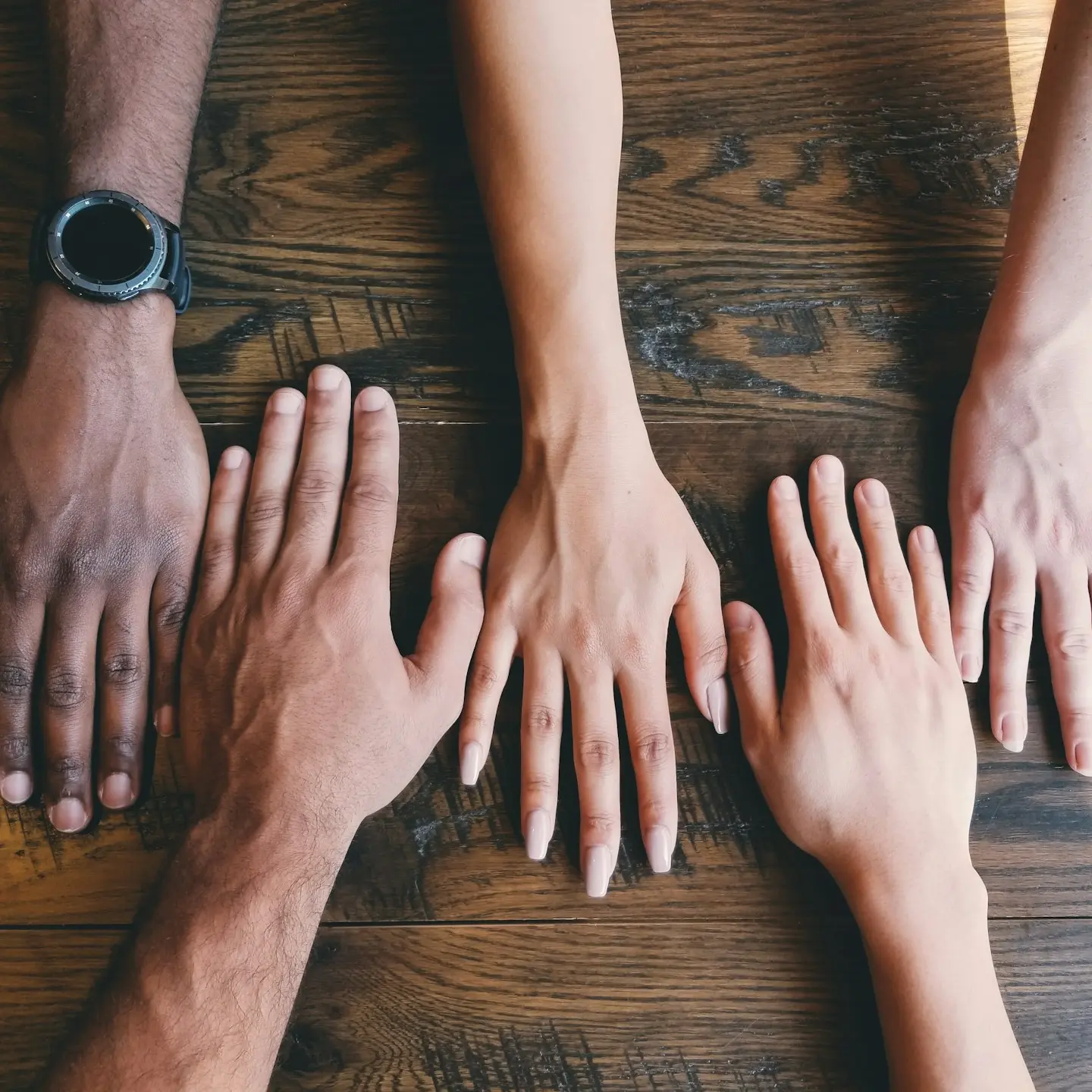 five human hands on brown surface